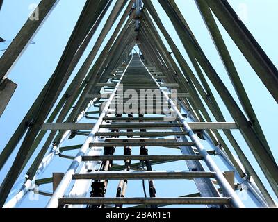 La fotografia offre una prospettiva verso l'alto della struttura interna di una torre di telecomunicazioni. L'immagine rivela la complessa struttura in acciaio che c Foto Stock