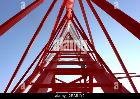 La fotografia offre una prospettiva verso l'alto della struttura interna di una torre di telecomunicazioni. L'immagine rivela la complessa struttura in acciaio che c Foto Stock