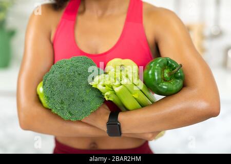 Giovane ragazza africana irriconoscibile che tiene vegetali verdi Foto Stock