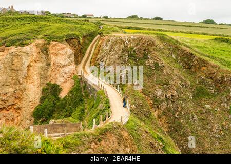 La Coupée, uno stretto istmo di terra tra il Grande Sark e Little Sark (primo piano) nelle Isole del canale del Regno Unito. Strada costruita nel 1945 dai prigionieri tedeschi. Foto Stock