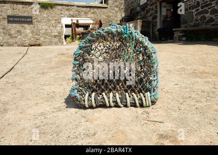 Aragosta pentola sul molo del piccolo villaggio di pescatori tradizionale di Cadgwith, Cornovaglia, Inghilterra, Regno Unito. Un vecchio pescatore è sullo sfondo Foto Stock