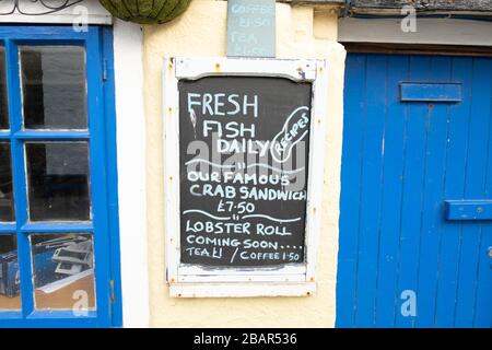 Tradizionale vecchio cartello da lavagna fuori negozio di pesce - pesce fresco tutti i giorni, famoso panino granchio, nel villaggio di pescatori di Cadgwith, Cornovaglia, Inghilterra Foto Stock