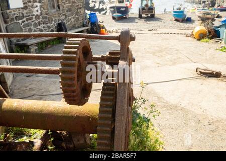 Vecchio verricello arrugginito con ingranaggio dentato e cavo utilizzato per verricello barche da pesca sulla spiaggia nel villaggio di Cadgwith, Cornovaglia, Inghilterra Foto Stock