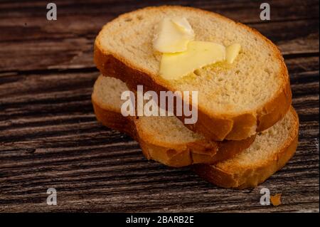 Toast di grano fresco con burro su fondo di legno. Primo piano Foto Stock