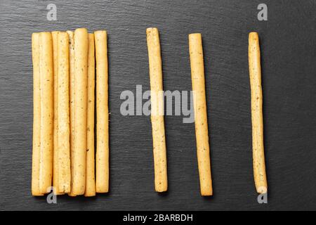 Tradizionale spuntino italiano, pane - grissini. Su un tavolo in pietra scura, vista dall'alto. Foto Stock