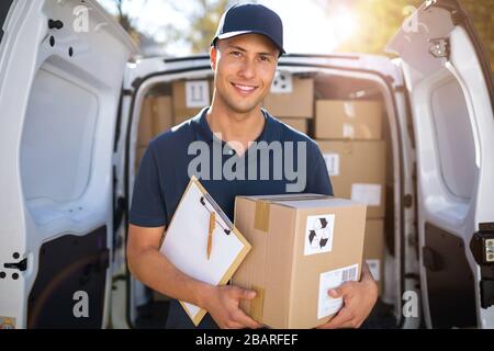 Sorridente uomo di consegna con il suo furgone Foto Stock