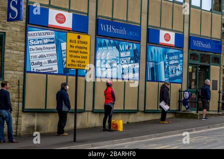 I clienti che fanno la coda fuori dall'ufficio postale, Holmfirth sabato mattina 28 marzo 2020 durante il blocco a causa della pandemia del virus corono. Foto Stock