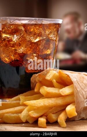 Fast food patatine fritte, cola con ghiaccio e un uomo mangiare in background Foto Stock