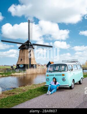 Alkmaar Olanda Aprile 2019, un classico furgone auto d'epoca parcheggiato da un mulino a vento storico in Olanda, il Classic Minny Green e il White VW Camper Van Foto Stock