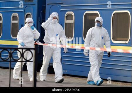 Kiev, Ucraina. 29 marzo 2020. Il personale che indossa abiti protettivi cammina per controllare i passeggeri che sono stati evacuati in treno dalla Russia, a causa della diffusione del coronavirus COVID-19, all'arrivo alla stazione ferroviaria centrale di Kiev, Ucraina, il 29 marzo 2020. I cittadini ucraini che, a causa di misure restrittive in relazione alla quarantena a causa del coronavirus diffuso COVID-19 non sono in grado di attraversare il confine, sono stati evacuati dal treno speciale dalla Russia. Credit: Serg Glovny/ZUMA Wire/Alamy Live News Foto Stock