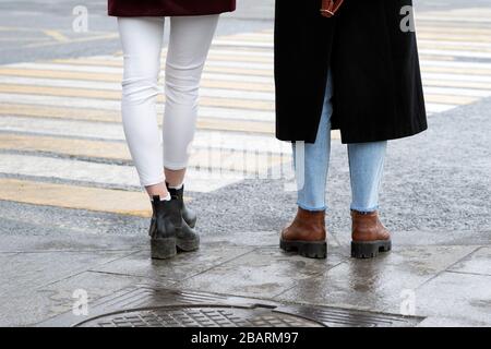 Gambe di due ragazze vicino al passaggio pedonale in attesa. Sfondo. Foto Stock