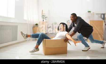 Marito americano africano che rotola sua moglie in scatola di cartone Foto Stock