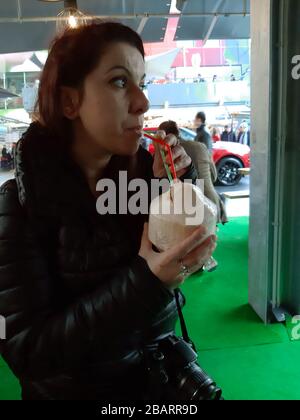 la ragazza in inverno beve il succo di latte da una frutta di cocco con cannucce colorate nel mercato di rotterdam Foto Stock