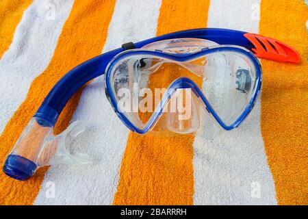 Maschera per snorkeling e immersioni su un asciugamano a righe bianche e gialle Foto Stock