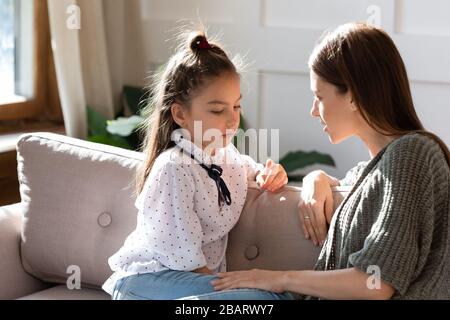 Sconvolto la piccola scolaretta che ha una conversazione fiduciosa con la madre. Foto Stock