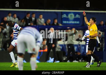 Il Queens Park Rangers' Samba Diakite (a sinistra) viene inviato dall'arbitro Mark Clattenburg (a destra) Foto Stock