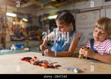 Le ragazze piccole che cooperano mentre fanno un robot Foto Stock