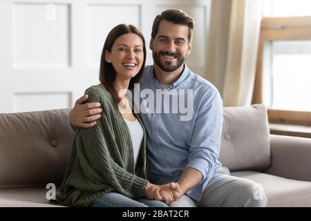 Ritratto di giovane coppia sposata felice seduto sul divano. Foto Stock