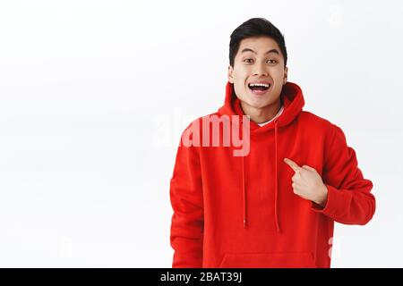 Ritratto di emozionato, felice uomo sorridente in felpa rossa puntando a se stesso come essere scelto o selezionato, raggiungere l'obiettivo, parlare obiettivo personale, in piedi Foto Stock