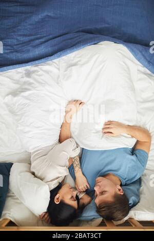 Sopra la vista in giovane coppia moderna che dorme insieme in blu e mentre le lenzuola, copia spazio Foto Stock