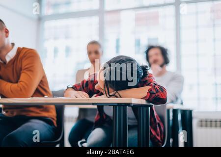 La giovane donna si annoiò e si frustrò con la testa giù sulla scrivania Foto Stock