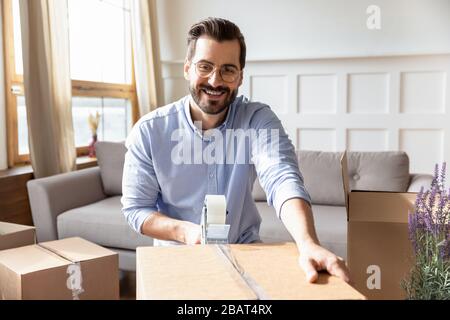 Sorridente giovane uomo bearded che impacchettano gli effetti personali in scatole di cartone. Foto Stock