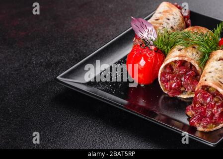 Delizioso tartaro di manzo fresco con toast su un piatto quadrato nero su sfondo scuro Foto Stock