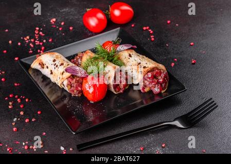 Delizioso tartaro di manzo fresco con toast su un piatto quadrato nero su sfondo scuro Foto Stock