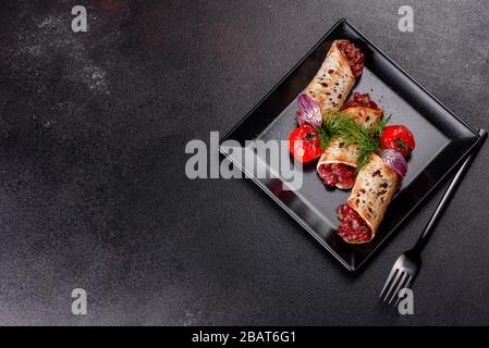 Delizioso tartaro di manzo fresco con toast su un piatto quadrato nero su sfondo scuro Foto Stock