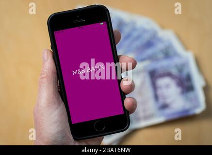 Una donna che utilizza l'app M&S Bank su un telefono cellulare. (Solo per uso editoriale) Foto Stock