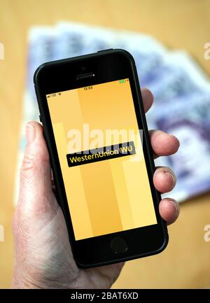 Una donna che utilizza l'app Western Union su un telefono cellulare. (Solo per uso editoriale) Foto Stock