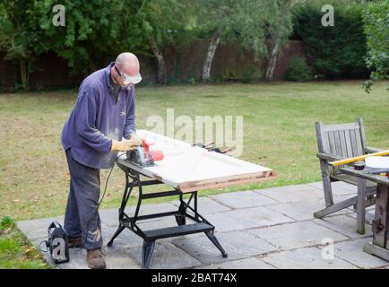 Fai da te Falegnameria e miglioramento casa, uomo che utilizza una sega circolare per ridimensionare una porta di legno, Regno Unito Foto Stock