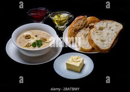 Farinata d'avena con banane fresche condusse con miele su sfondo nero. Foto Stock