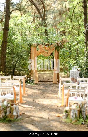 Altare giallo per matrimoni e sedie bianche in giardino. Foto Stock