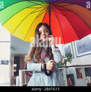 Ritratto di una ragazza miserabile, che tiene un ombrello colorato all'interno della casa Foto Stock