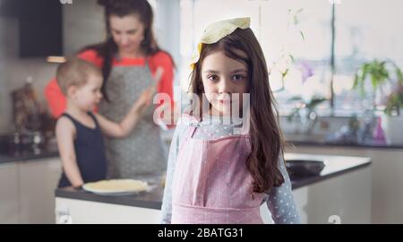 Famiglia allegro facendo crepes deliziosi nella cucina di casa Foto Stock