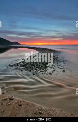 Sunrise over Lyme Bay con Golden Cap, Charmouth, Jurassic Coast, Dorset, Inghilterra Foto Stock