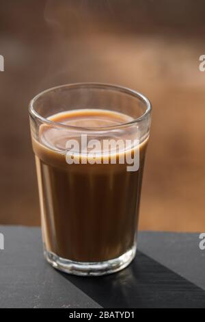 Tè di masala indiano di vetro sfaccettato su un asse di legno Foto Stock