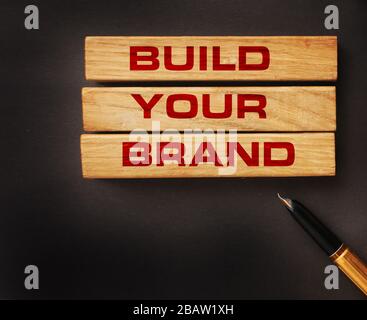 Costruisci il tuo marchio scritto su blocchi di legno con sfondo vintage stile. Branding rebranding concetto di marketing Foto Stock