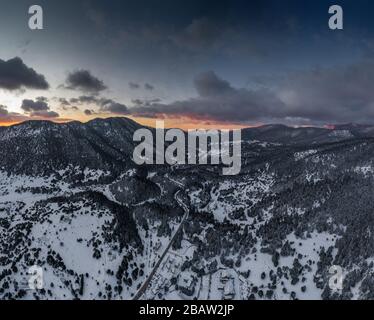 La vista aerea di un tramonto sulla montagna a Arahova, Grecia, una vista della valle sotto con alberi coperti di neve, colori del tramonto Foto Stock