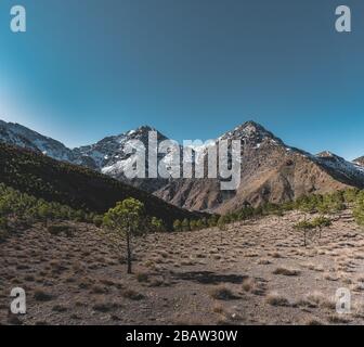 Vetta innevata del monte Toubkal in Marocco durante la primavera in una giornata di sole. Catena montuosa dell'Atlante vicino a Marrakech. Inizia per il sentiero escursionistico. Foto Stock