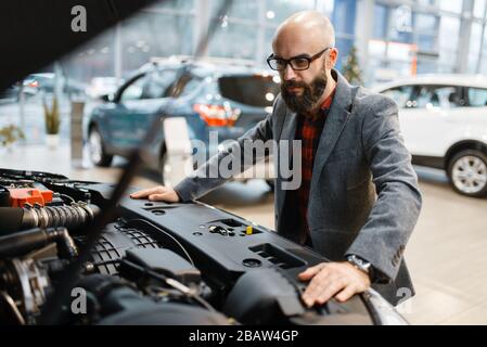 Uomo al nuovo veicolo con cofano aperto, concessionario auto Foto Stock