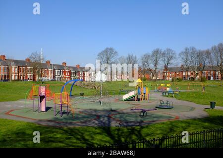 Derby Park a Bootle Liverpool è quasi deserta e l'area giochi per bambini è chiusa. La gente tiene la loro distanza al supermercato a causa di COVID-19. Foto Stock