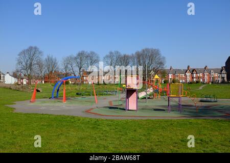 Derby Park a Bootle Liverpool è quasi deserta e l'area giochi per bambini è chiusa. La gente tiene la loro distanza al supermercato a causa di COVID-19. Foto Stock