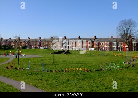 Derby Park a Bootle Liverpool è quasi deserta e l'area giochi per bambini è chiusa. La gente tiene la loro distanza al supermercato a causa di COVID-19. Foto Stock