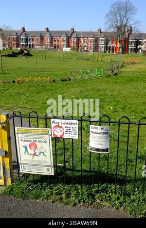 Derby Park a Bootle Liverpool è quasi deserta e l'area giochi per bambini è chiusa. La gente tiene la loro distanza al supermercato a causa di COVID-19. Foto Stock