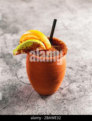 Tradizionale bevanda alcolica messicana in tazza di terracotta con spezie arancio calce sul bordo delle tazze Foto Stock