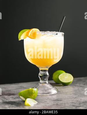 Limone margarita messicano con sfondo nero e superficie grigia grigia con lime a fette e arancio Foto Stock