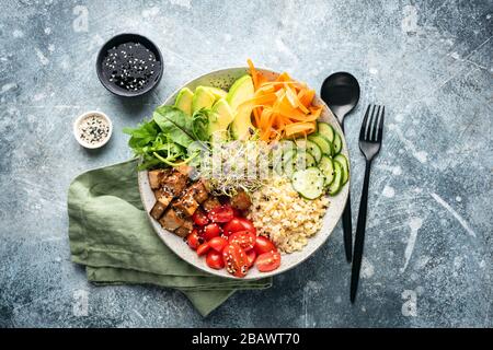 Ciotola di buddha vegano con tofu, verdure, avocado servito con salsa di soia e semi di sesamo. Vista dall'alto Foto Stock