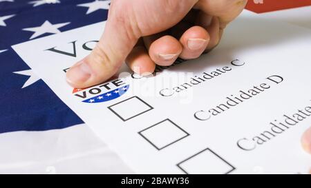 La mano dell'uomo segna il candidato selezionato con ho votato oggi l'adesivo su un voto di carta per le elezioni presidenziali degli Stati Uniti. Foto Stock